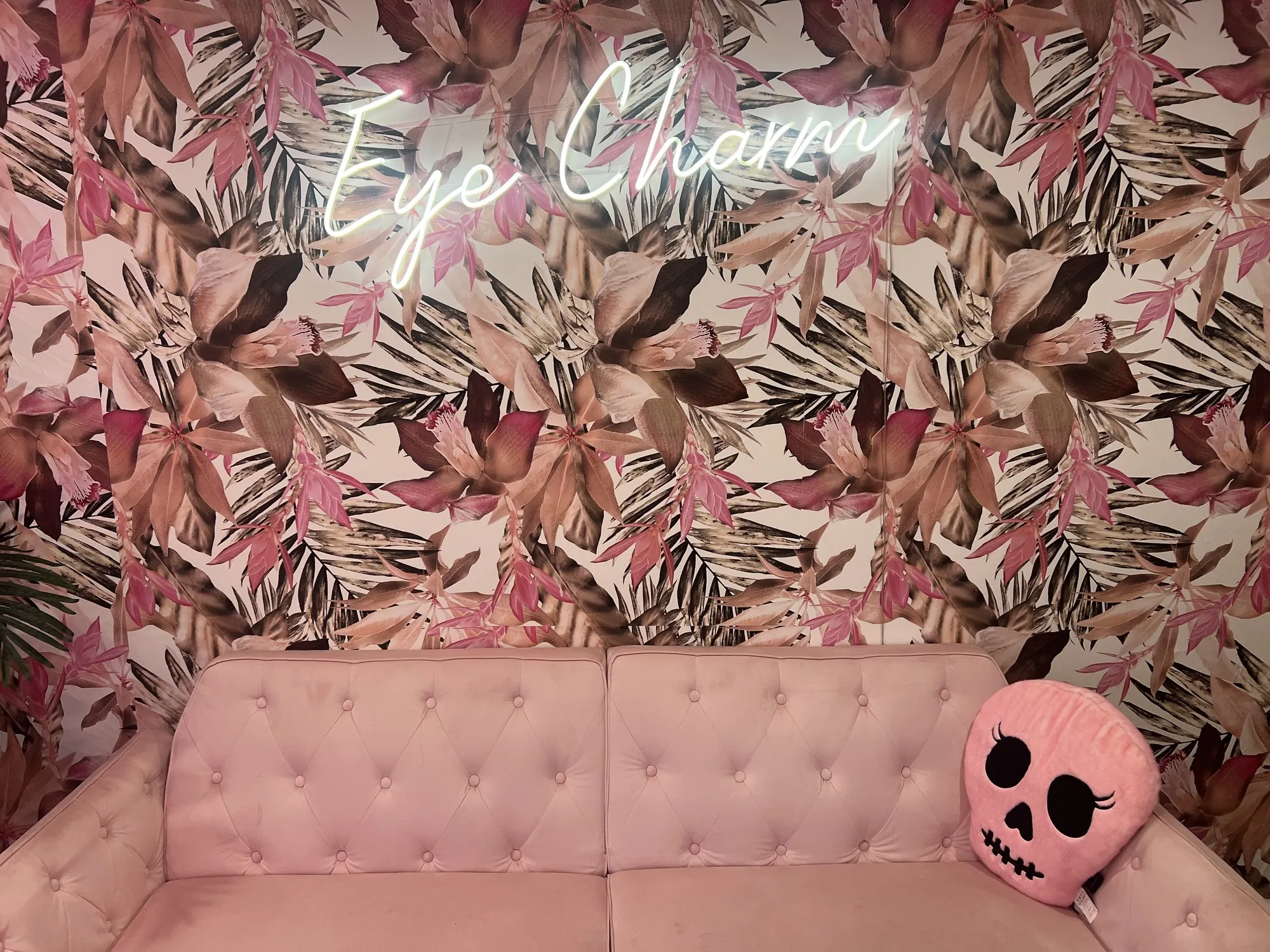 The Eye Charm neon sign above a blush velvet sofa in the studio lounge in Hyde Park, Austin